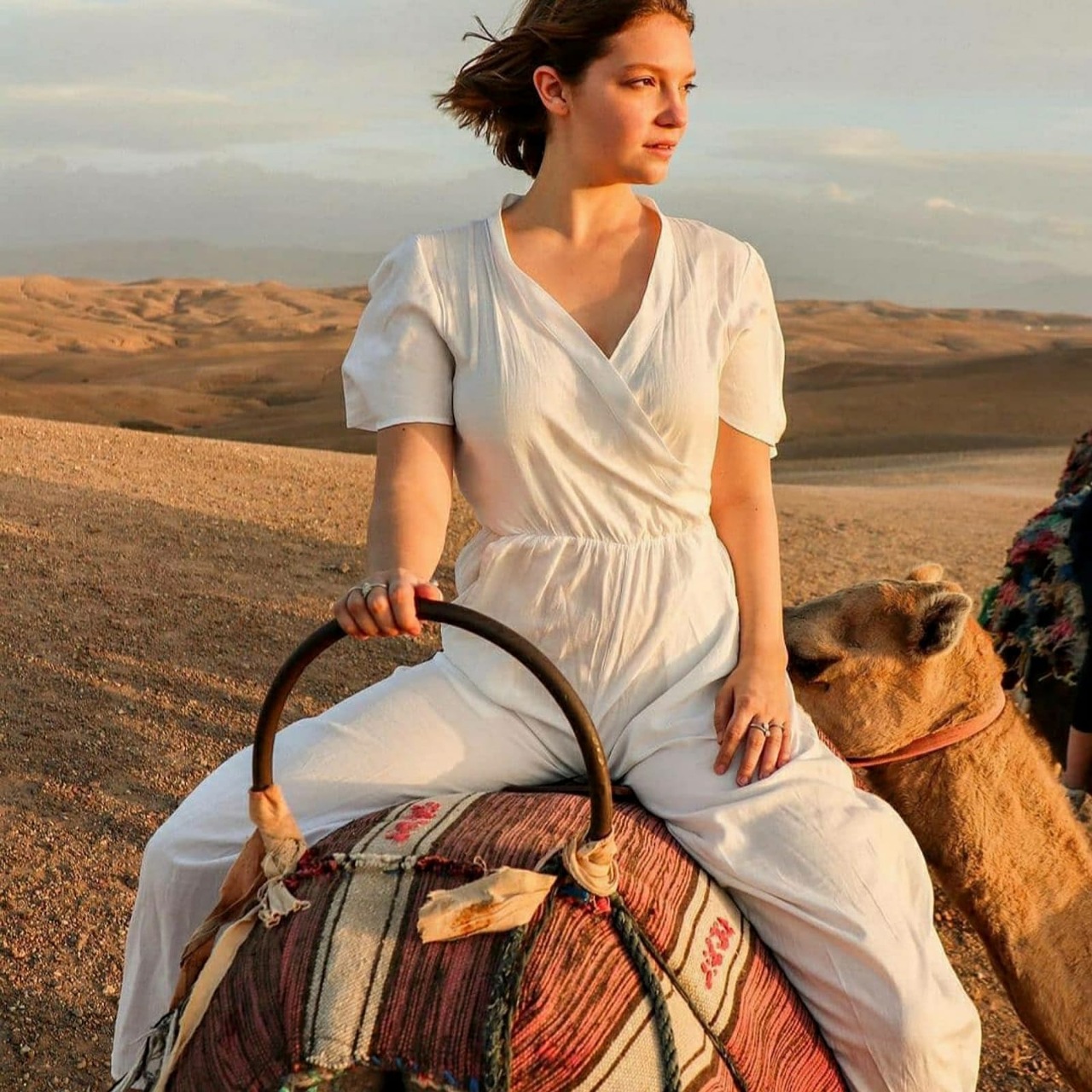 Viajero con túnica bereber azul durante un paseo en camello al atardecer en el desierto de Agafay, cerca de Marrakech