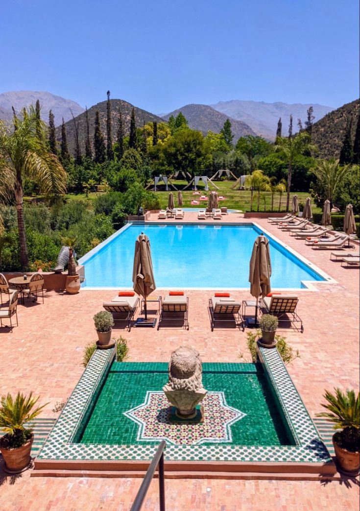The main swimming pool at Kasbah Tamadot with a zellige-tiled fountain, loungers and gardens rising towards the High Atlas