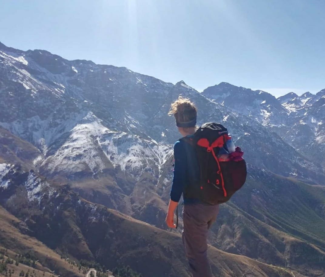 Montañeros subiendo una cresta rocosa en el Alto Atlas con el monte Toubkal al fondo