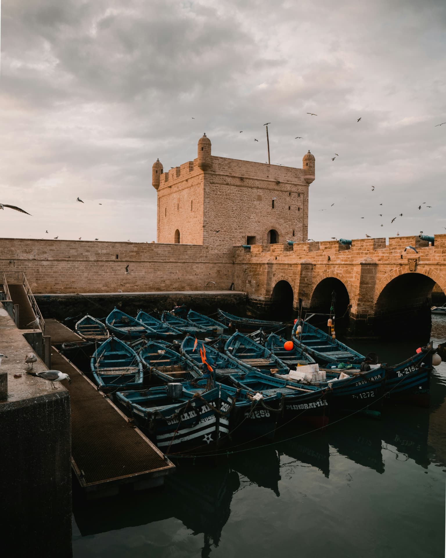 Barcos de pesca azules amarrados junto a las murallas blancas de Essaouira en la costa atlántica