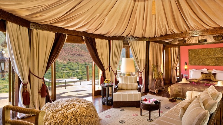 Interior of a Berber tent at Kasbah Tamadot with a canopied bed, rugs, lanterns and canvas walls open to the mountain view