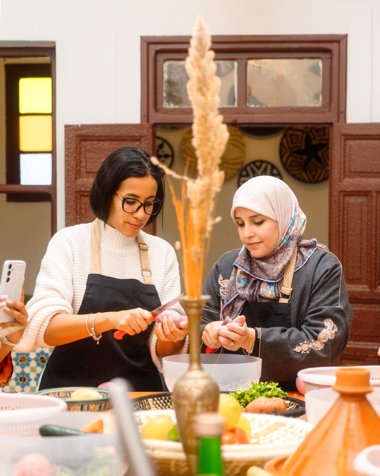 Two guests in aprons slicing onions at the preparation table during a Marrakech cooking class