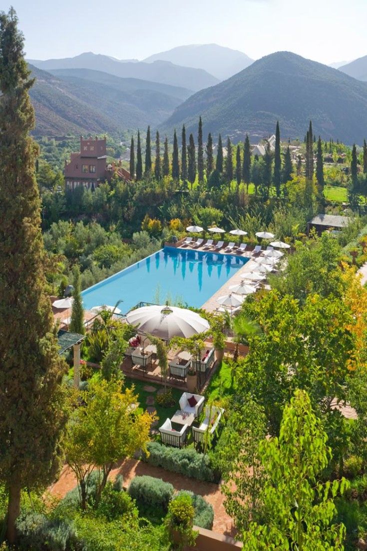 Terraced gardens and pool at Kasbah Tamadot seen from above, looking out across the Asni valley to the High Atlas ridgeline