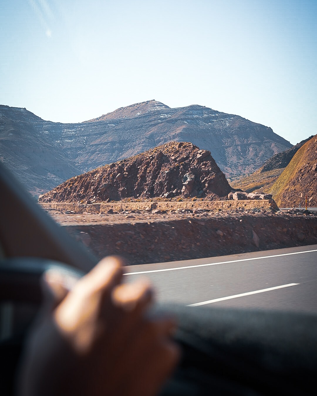 Bare Atlas ridges and a mountain pass seen from the window of a moving vehicle