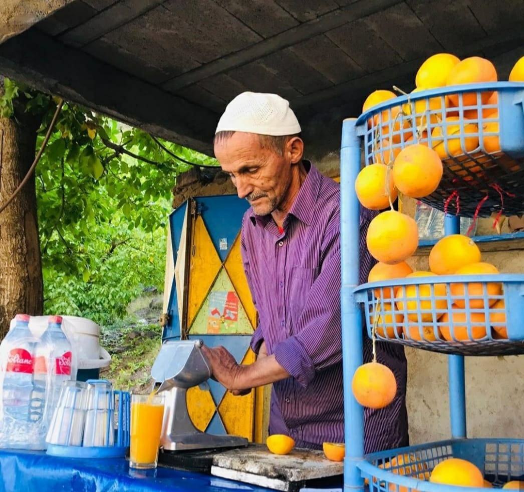 A vendor pressing fresh orange juice at a roadside stall in the Atlas foothills