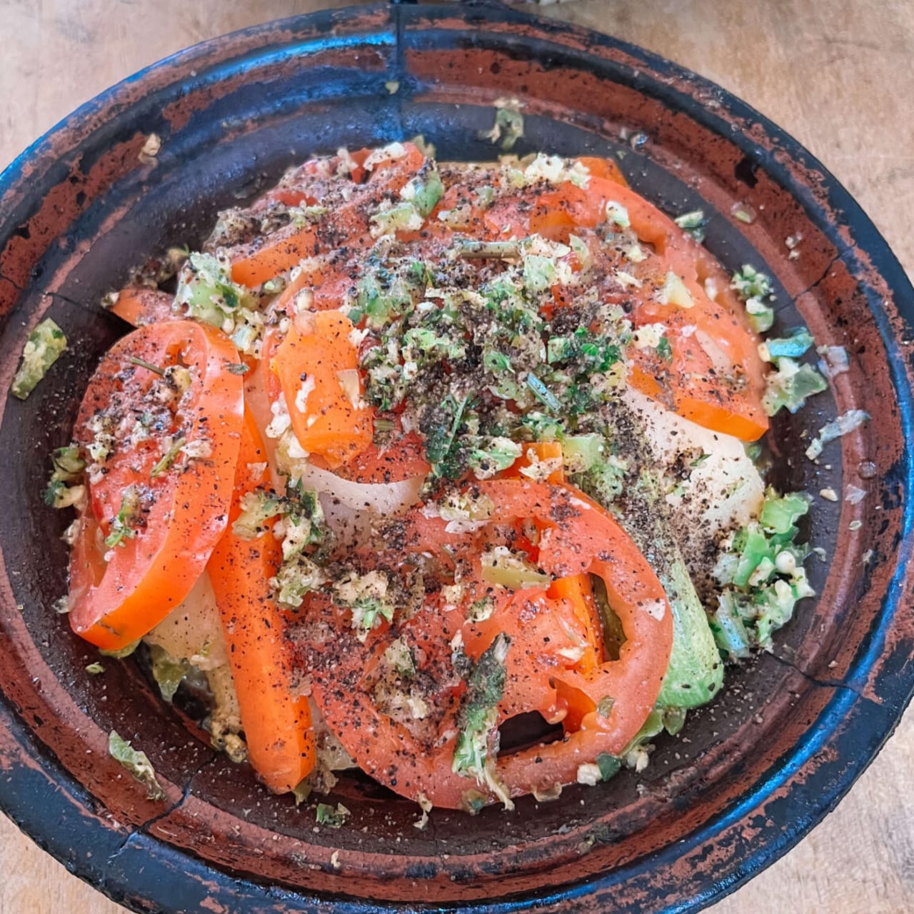 Un tagine de verduras con tomate, zanahoria y hierbas servido en un plato de barro