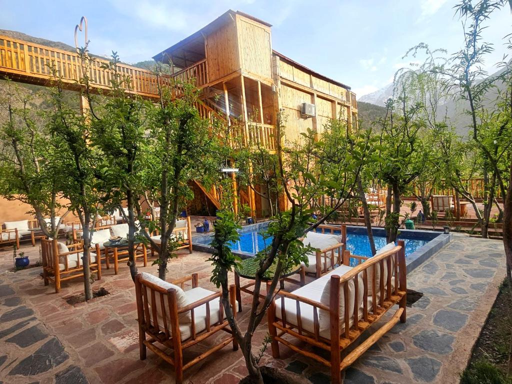 Afla Sky Views timber lodge with an outdoor pool, garden seating and High Atlas peaks behind