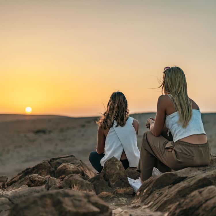 Two travellers watching the Agafay sunset from a rocky viewpoint outside Marrakech