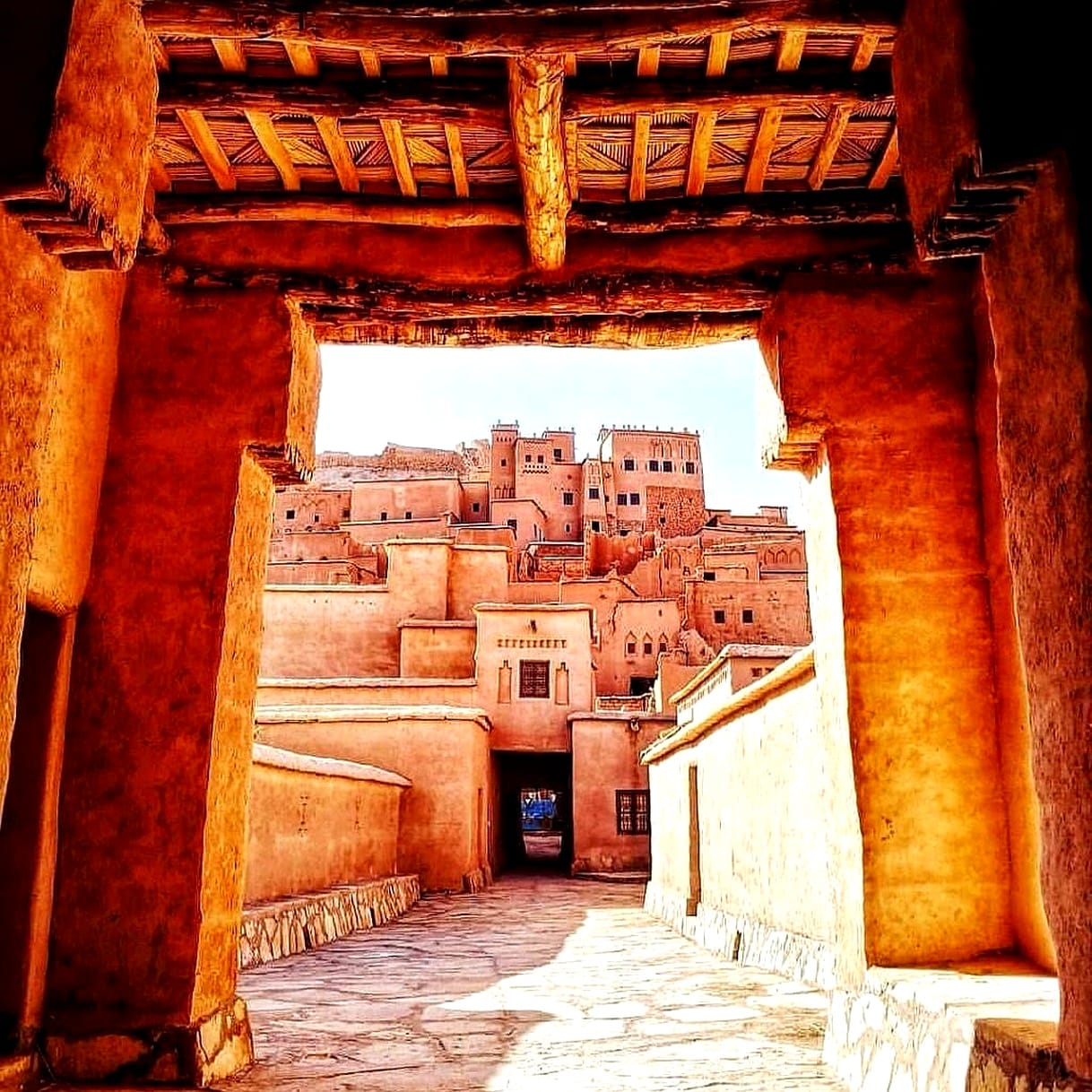Aït Ben Haddou framed by a carved wooden kasbah gateway in warm afternoon light