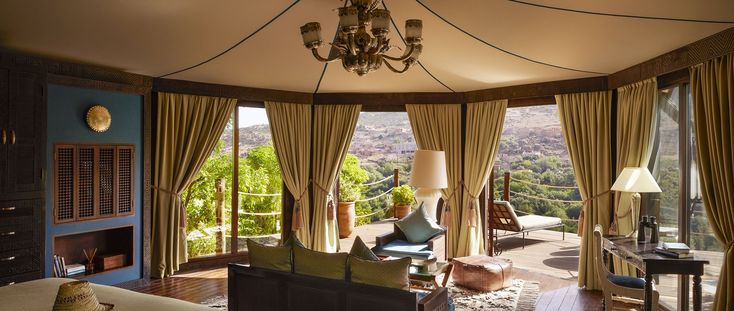 Inside a Berber tent at Kasbah Tamadot in daylight, with curtains drawn back onto a private terrace above the Asni valley