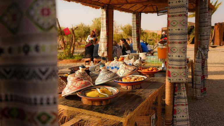 Moroccan breakfast table with tagine dishes under a shaded terrace