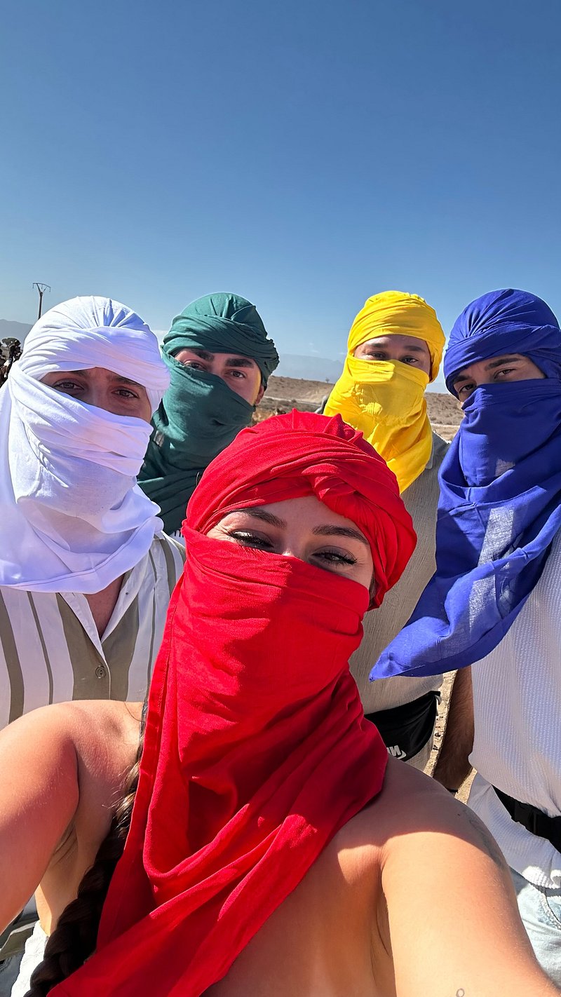 Five travellers wearing brightly coloured Berber turbans on a track in the Agafay stone desert