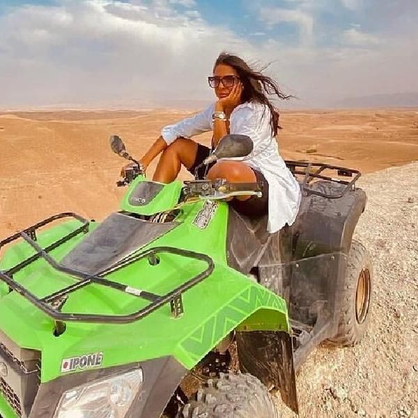 A visitor sitting on a green quad bike on the stony Agafay desert plateau