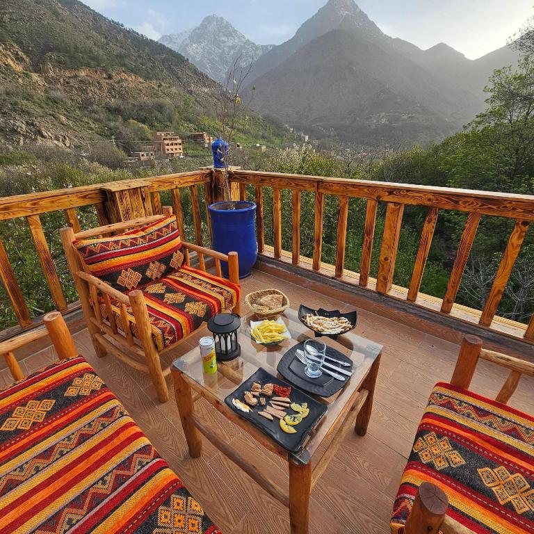 Wooden terrace at Afla Sky Views set with a meal, looking out over the valley and snow-topped Atlas peaks