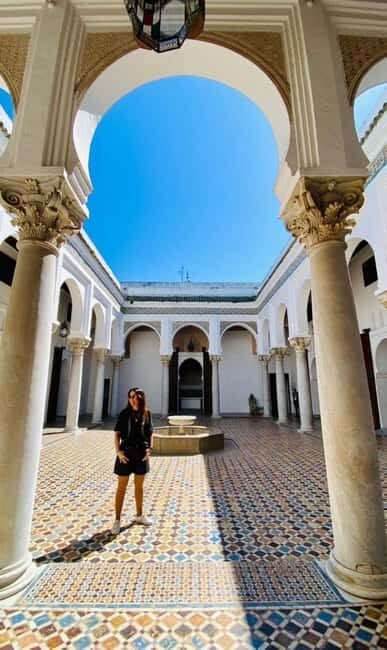 A tiled Moroccan courtyard with horseshoe arches, carved columns and a central fountain
