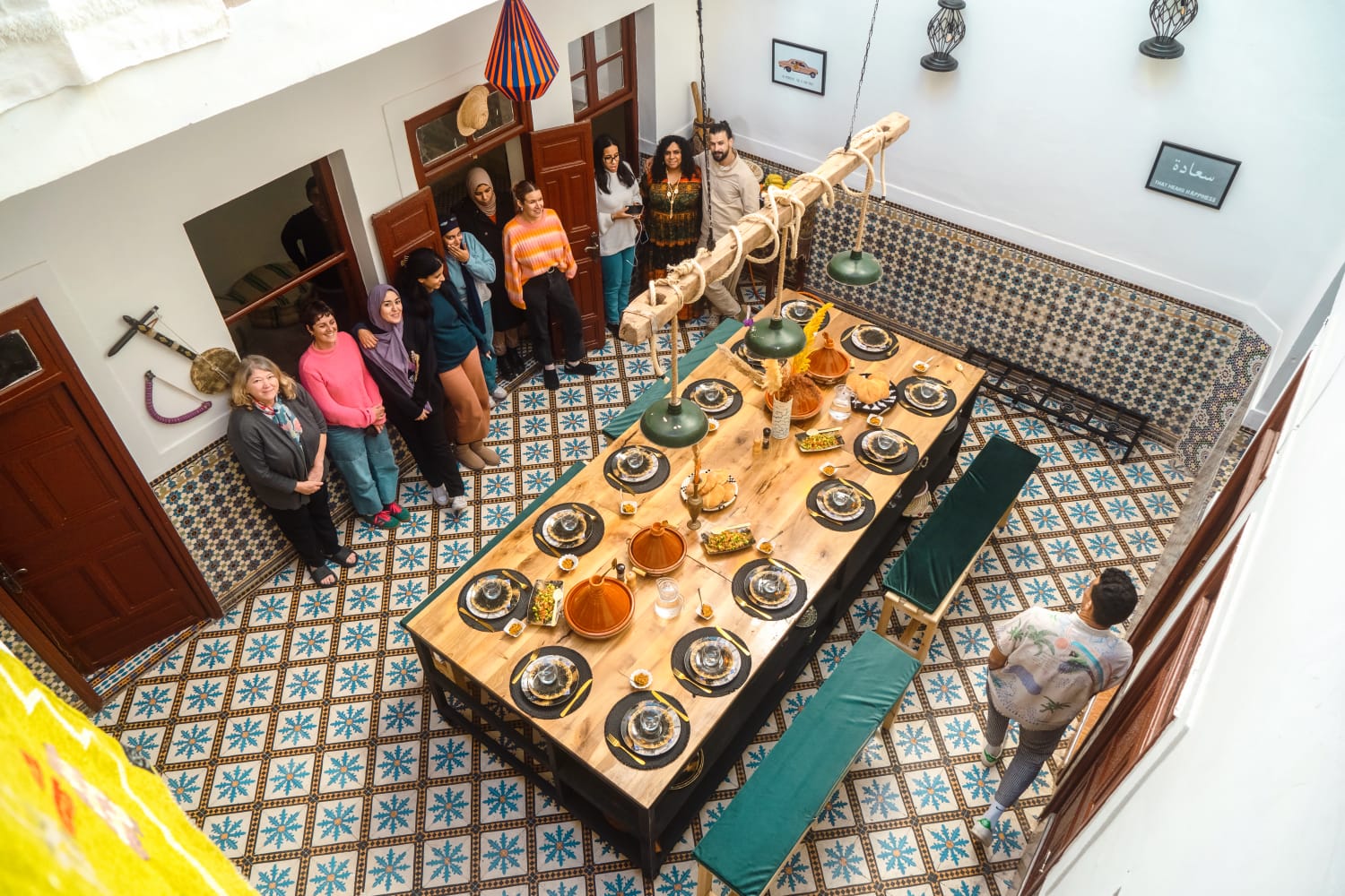 A cooking-class group standing beside the long riad table laid for the meal on patterned Moroccan tiles