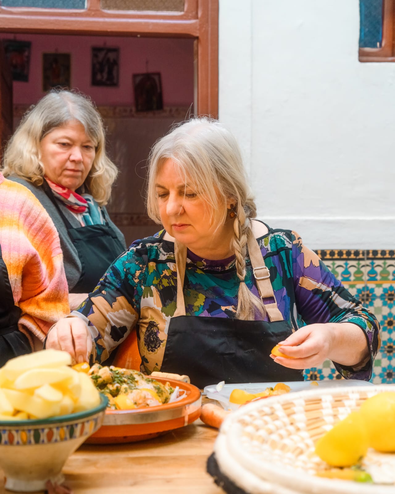Guests in aprons preparing a tagine with preserved lemons and potatoes at the cooking-class table