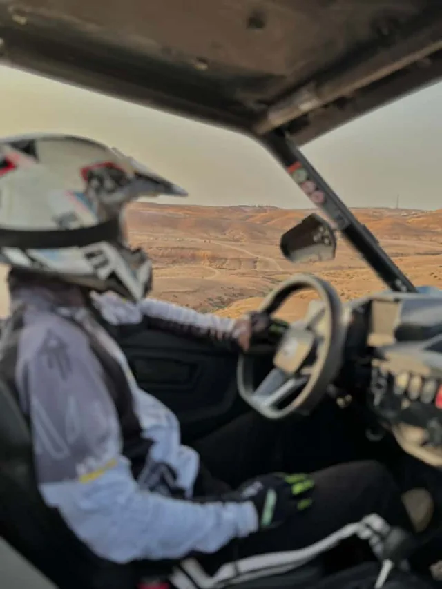 View from inside a desert buggy over the driver's shoulder, looking across the Agafay desert tracks