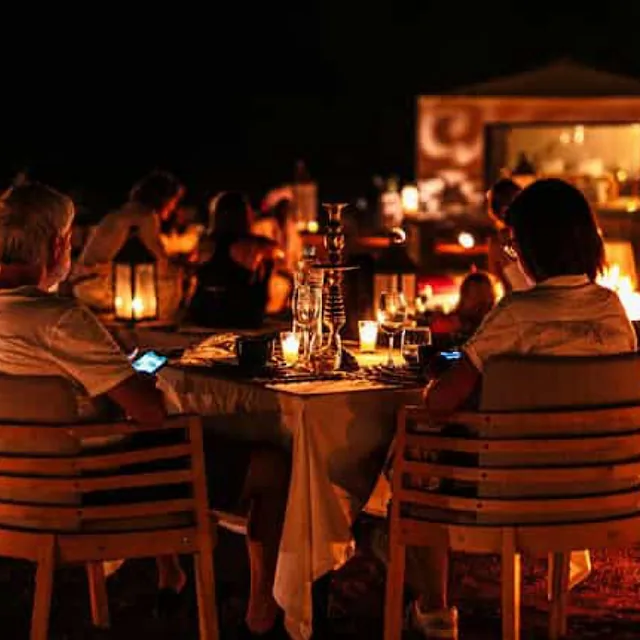 Candlelit dinner tables set out in the Agafay desert after dark