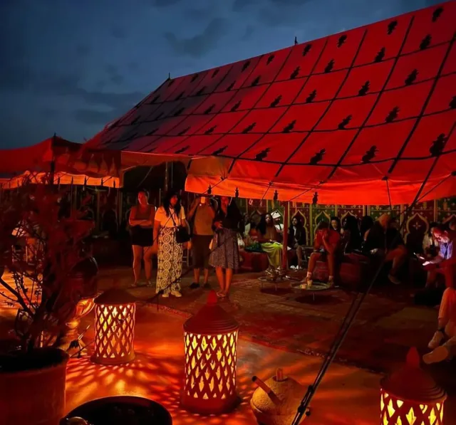 A red caidal tent lit up in the Agafay desert camp in the evening