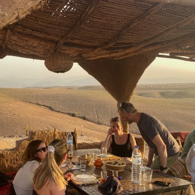 Guests sharing a Moroccan meal on a shaded desert terrace overlooking the Agafay valley