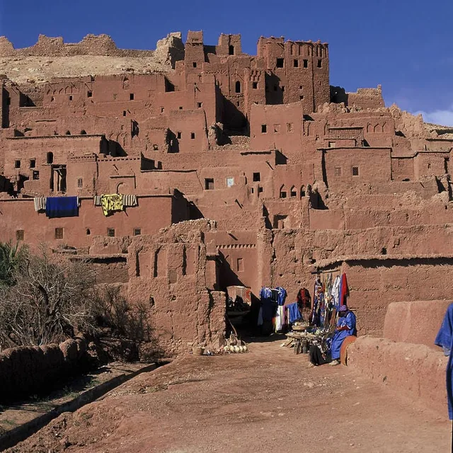 The red earthen walls of Aït Ben Haddou with craft stalls along the track below