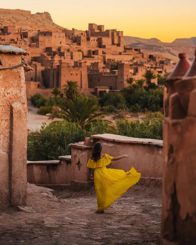 The earthen ksar of Aït Ben Haddou glowing at sunset above palm trees