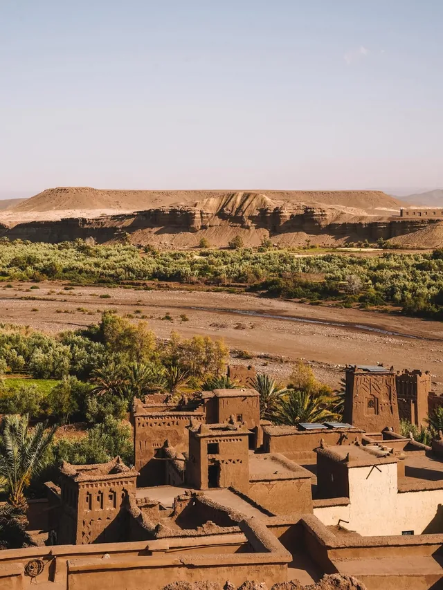 Aït Ben Haddou rooftops and palm gardens above the dry Ounila riverbed and desert plateau