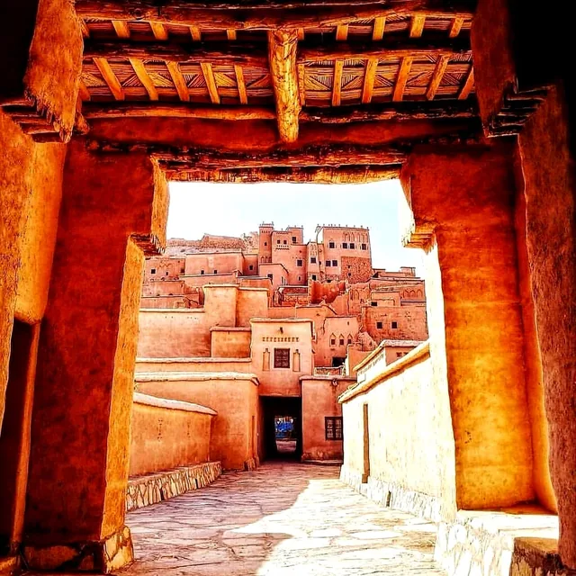 Aït Ben Haddou framed by a carved wooden kasbah gateway in warm afternoon light