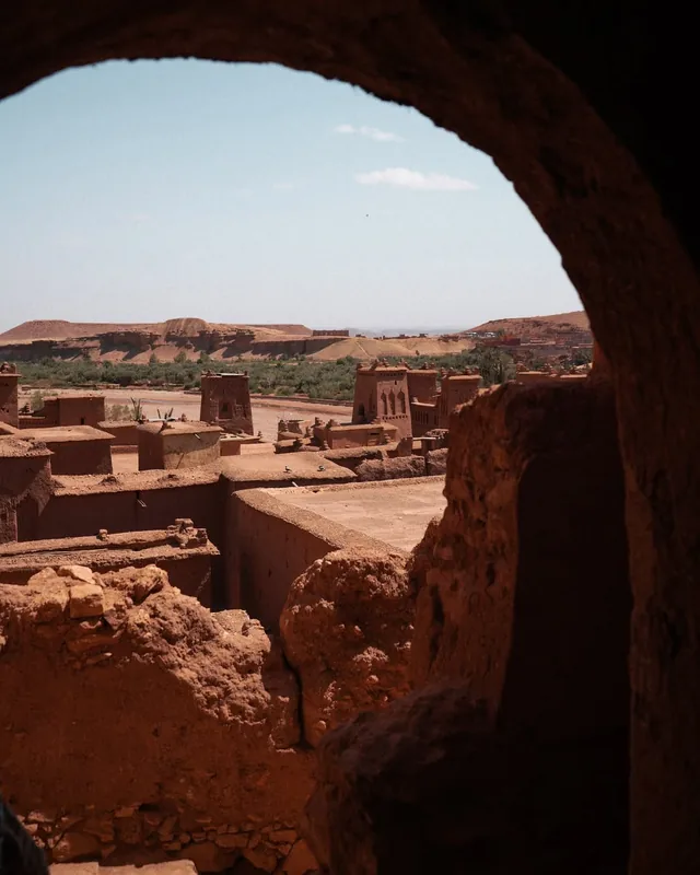 The towers and rooftops of Aït Ben Haddou framed by a rough earthen arch