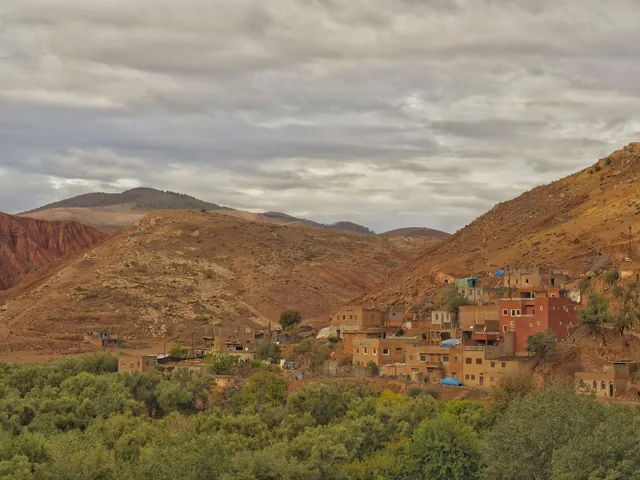 An Atlas valley village of red earth houses below bare ochre mountains
