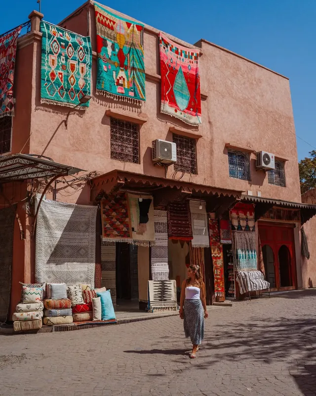 Berber rugs and kilims hung across a pink medina facade in the rug quarter