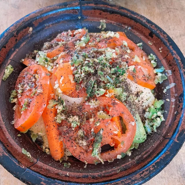 Un tagine de verduras con tomate, zanahoria y hierbas servido en un plato de barro