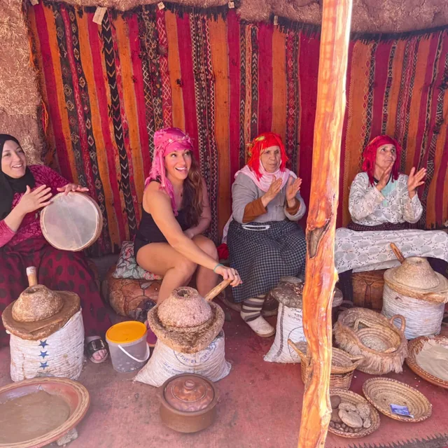 Berber women grinding argan nuts and playing drums inside a woven tent