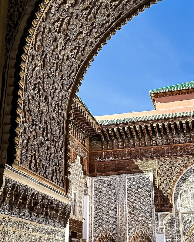 A finely carved arch and green tiled roof in the courtyard of Medersa Ben Youssef