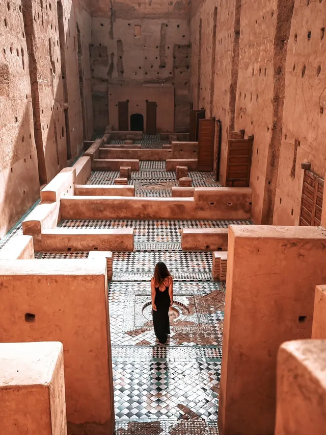 A visitor walking the sunken tiled courtyards of the El Badi Palace ruins