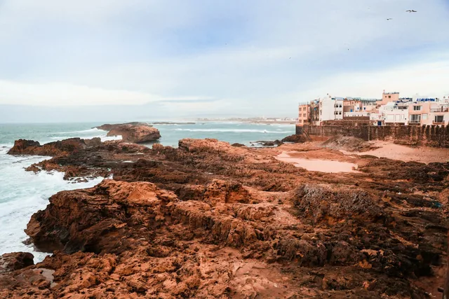 Waves breaking on the red rocks below the ramparts and white houses of Essaouira