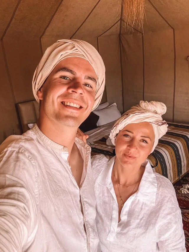 Two guests in white cotton and hand-tied turbans inside their desert camp tent