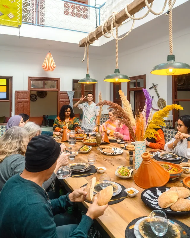 Guests seated around a shared tagine lunch in a bright riad courtyard