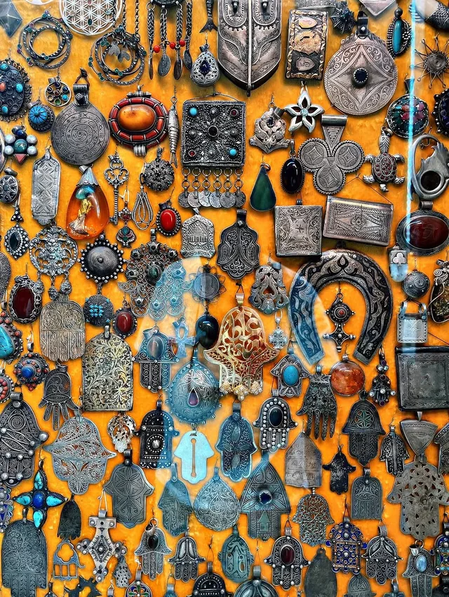 Wall of antique Berber silver pendants, hamsa hands and amber jewellery in a Marrakech shop