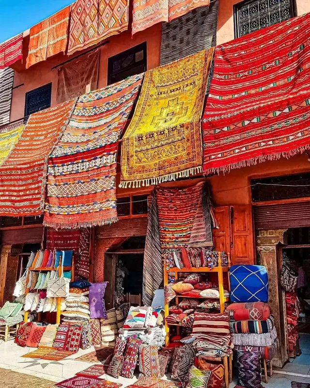 A Marrakech souk shopfront hung with bright Berber rugs, blankets and cushions