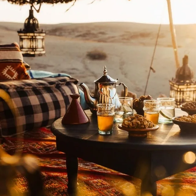 Mint tea, nuts and lanterns on a low table looking out over the desert at sunset