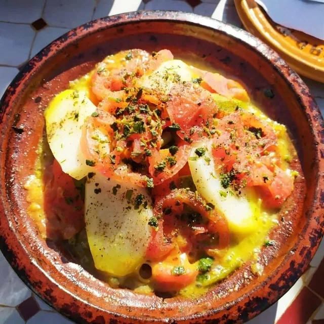A Moroccan vegetable tagine of tomato, potato and herbs steaming in a clay dish