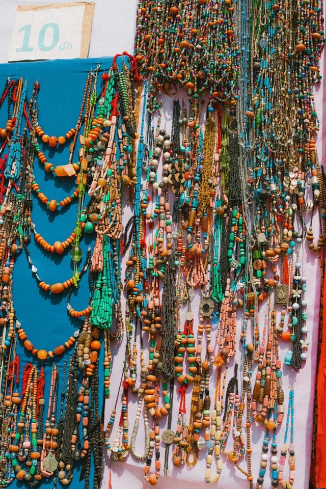 A market wall covered in colourful beaded Berber necklaces with a 10 dh price card