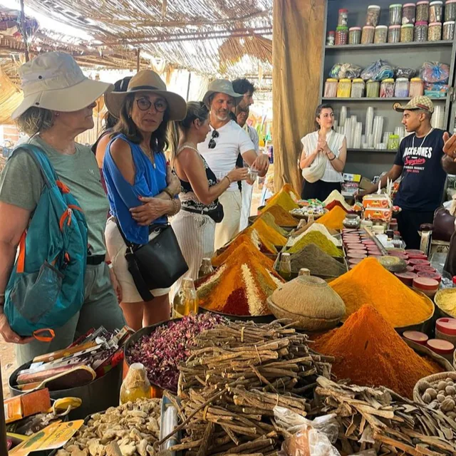 Visitors browsing cones of coloured spices, dried roses and herbs at a Moroccan market stall