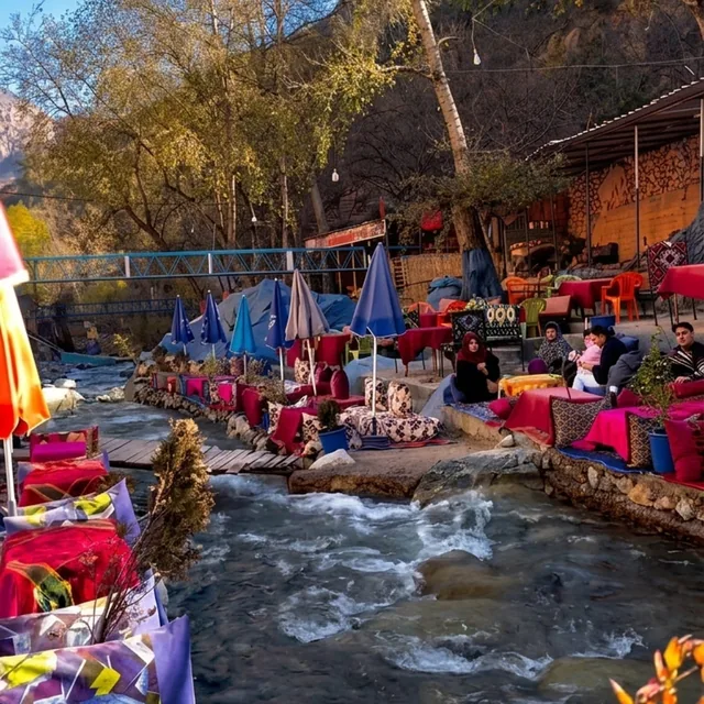 Riverside cushions and parasols beside the Ourika river under autumn trees