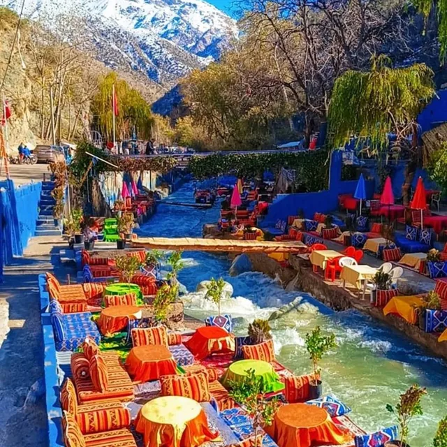 Colourful riverside cafés along the Ourika river with snow-capped High Atlas peaks behind