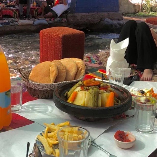 Vegetable tagine, bread and salad served on a low table right beside the river