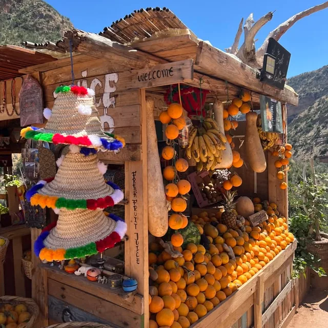 Roadside stall in the Ourika valley hung with oranges, bananas and straw hats selling fresh fruit juice