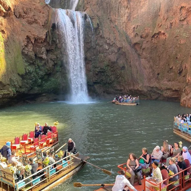 Colourful wooden boats carrying visitors on the plunge pool beneath Ouzoud waterfall